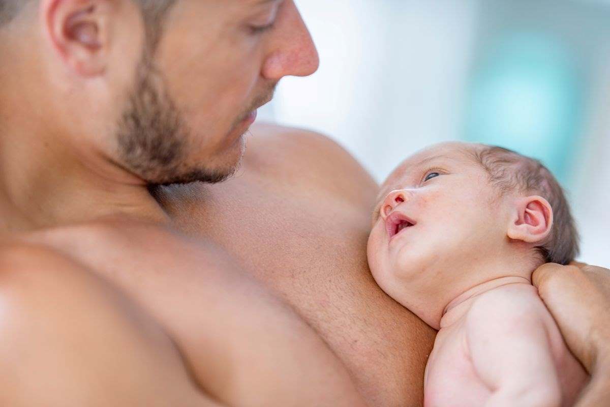 papà con neonato appoggiato sul suo torace nudo