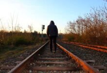 ragazzo che partecipa a sfida social estrema e cammina sui binari del treno