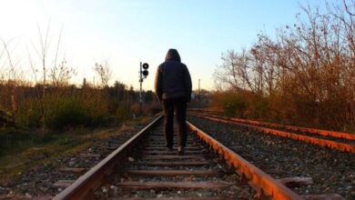 ragazzo che partecipa a sfida social estrema e cammina sui binari del treno