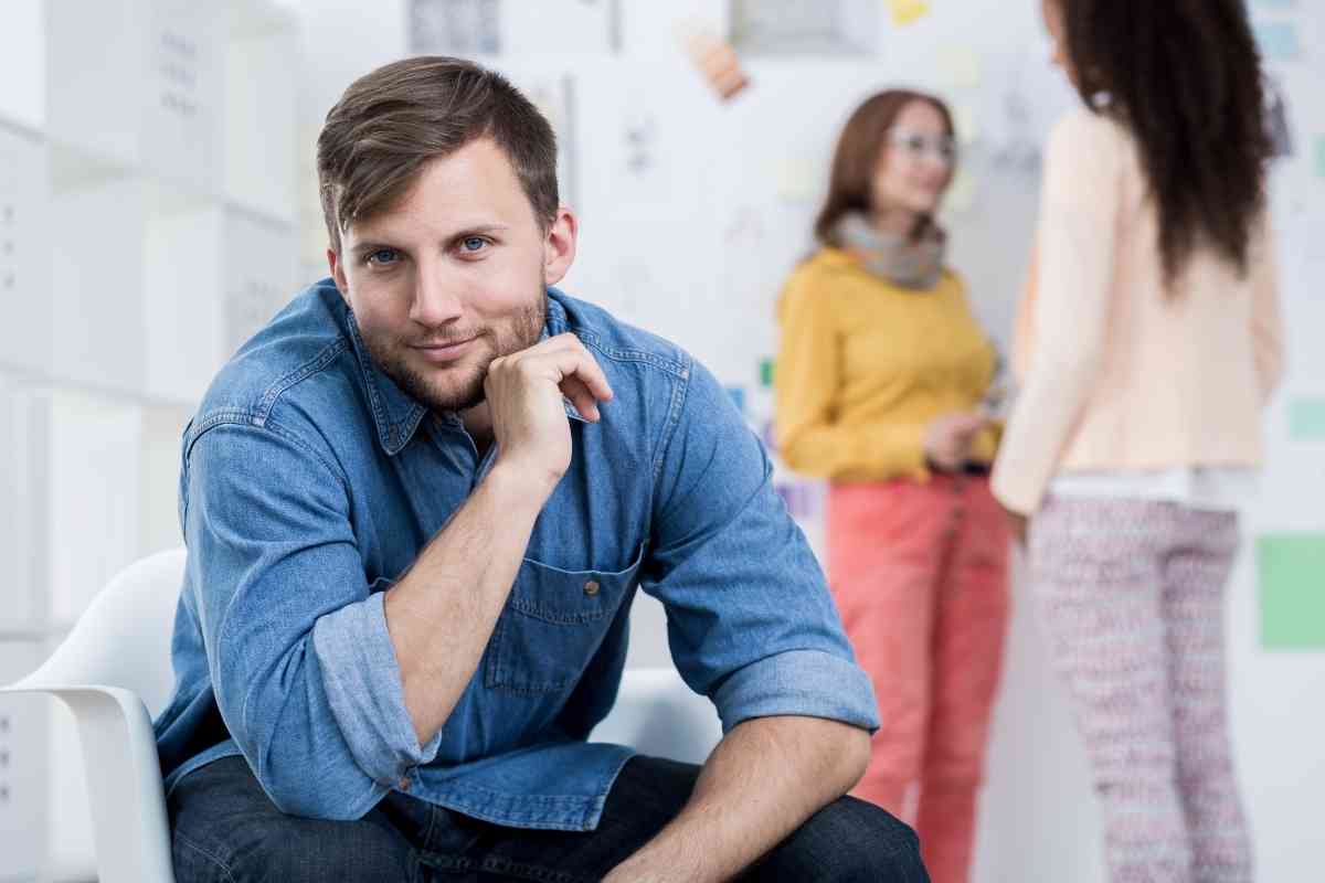 un uomo si mostra sicuro mentre due colleghe parlano male di lui