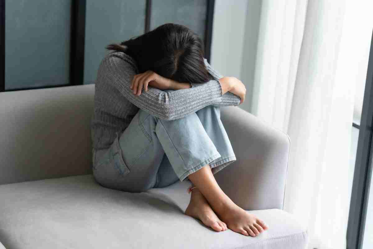 una ragazza in preda all'ansia seduta su un divano