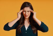 una ragazza si porta le mani alle tempie per alleviare il mal di testa