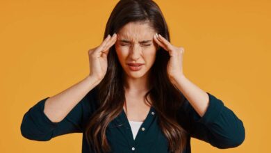 una ragazza si porta le mani alle tempie per alleviare il mal di testa