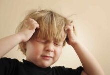 un bambino con le mani sulla testa perché sente dolore al cuoio capelluto