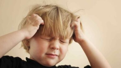un bambino con le mani sulla testa perché sente dolore al cuoio capelluto