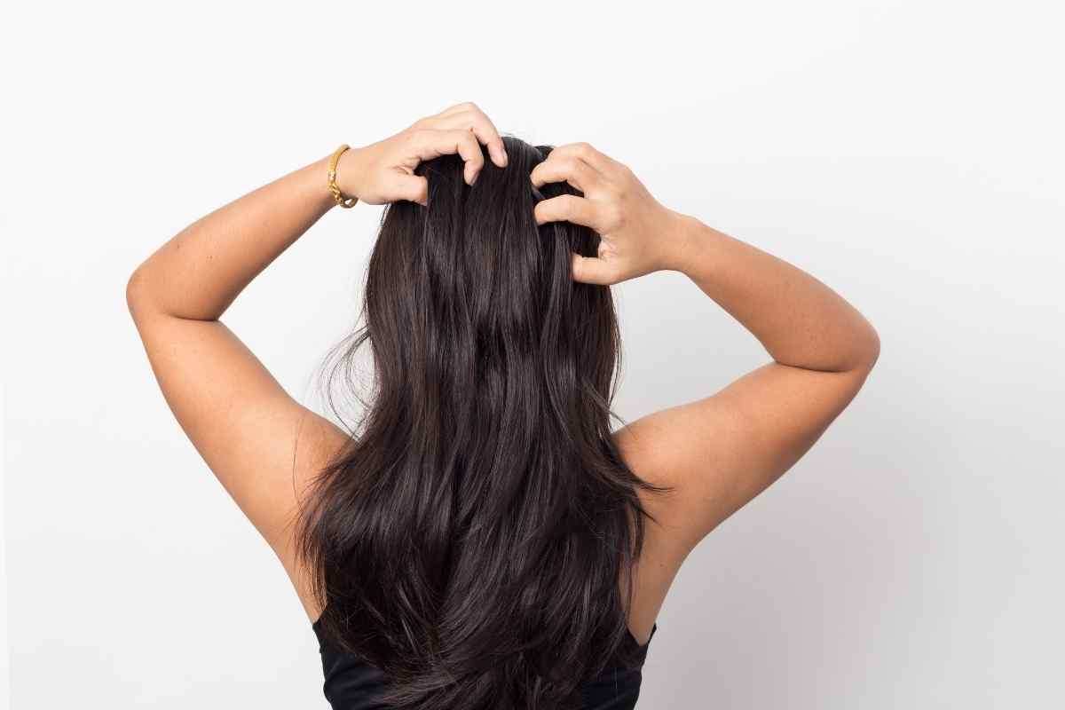 una donna si massaggia la zona del cuoio capelluto