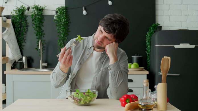 uomo depresso che mangia solo una insalata
