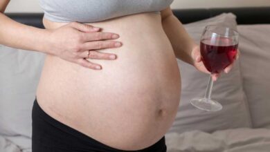 donna incinta che tiene in mano un bicchiere di vino rosso