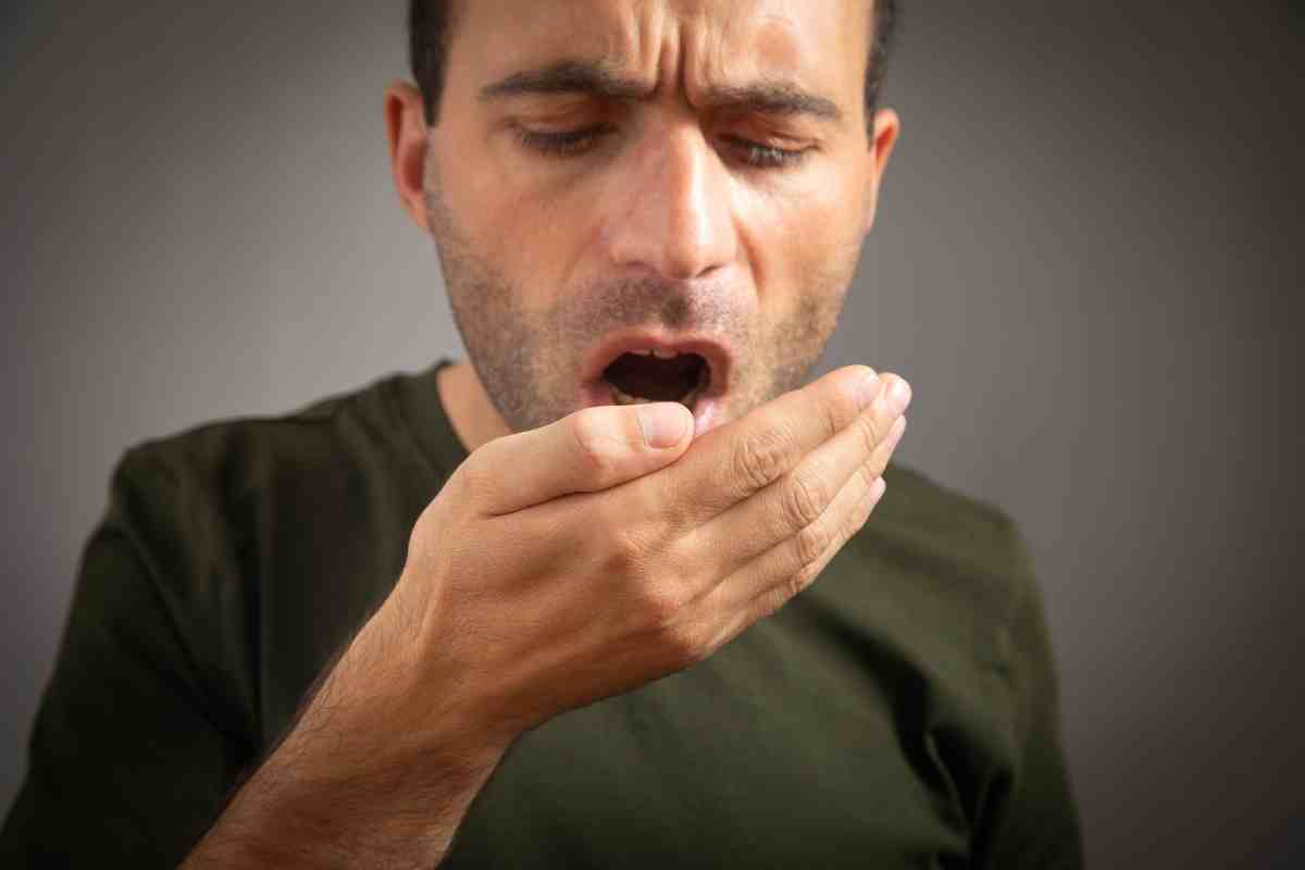 un uomo si controlla l'odore dell'alito