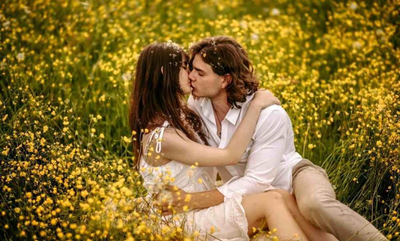 un ragazzo e una ragazza si baciano in un campo fiorito