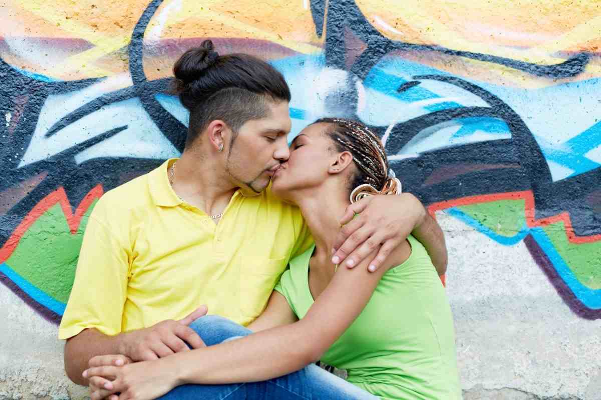 un ragazzo e una ragazza si baciano davanti a un murales