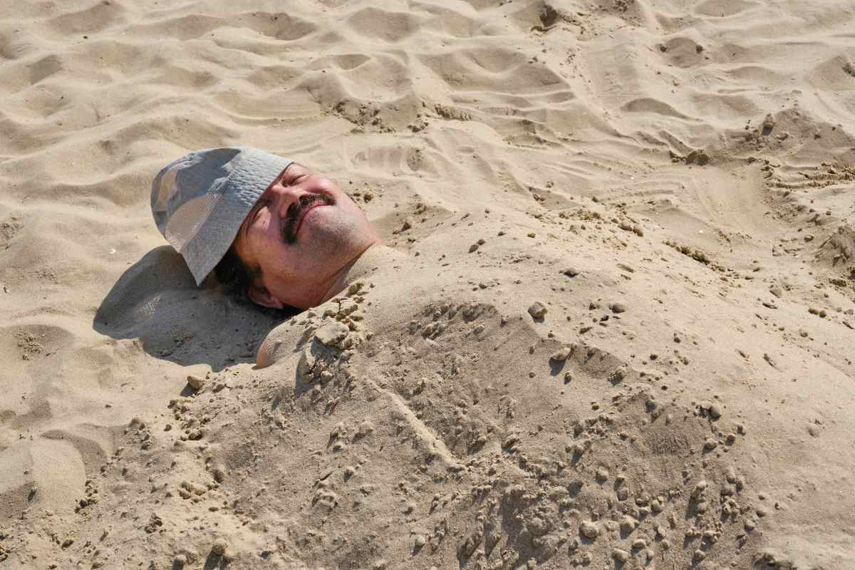un uomo esegue una sabbiatura in spiaggia