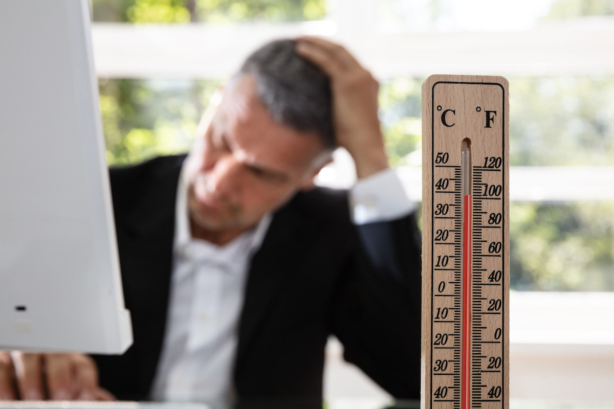 un uomo in ufficio non riesce a concentrarsi per il troppo caldo