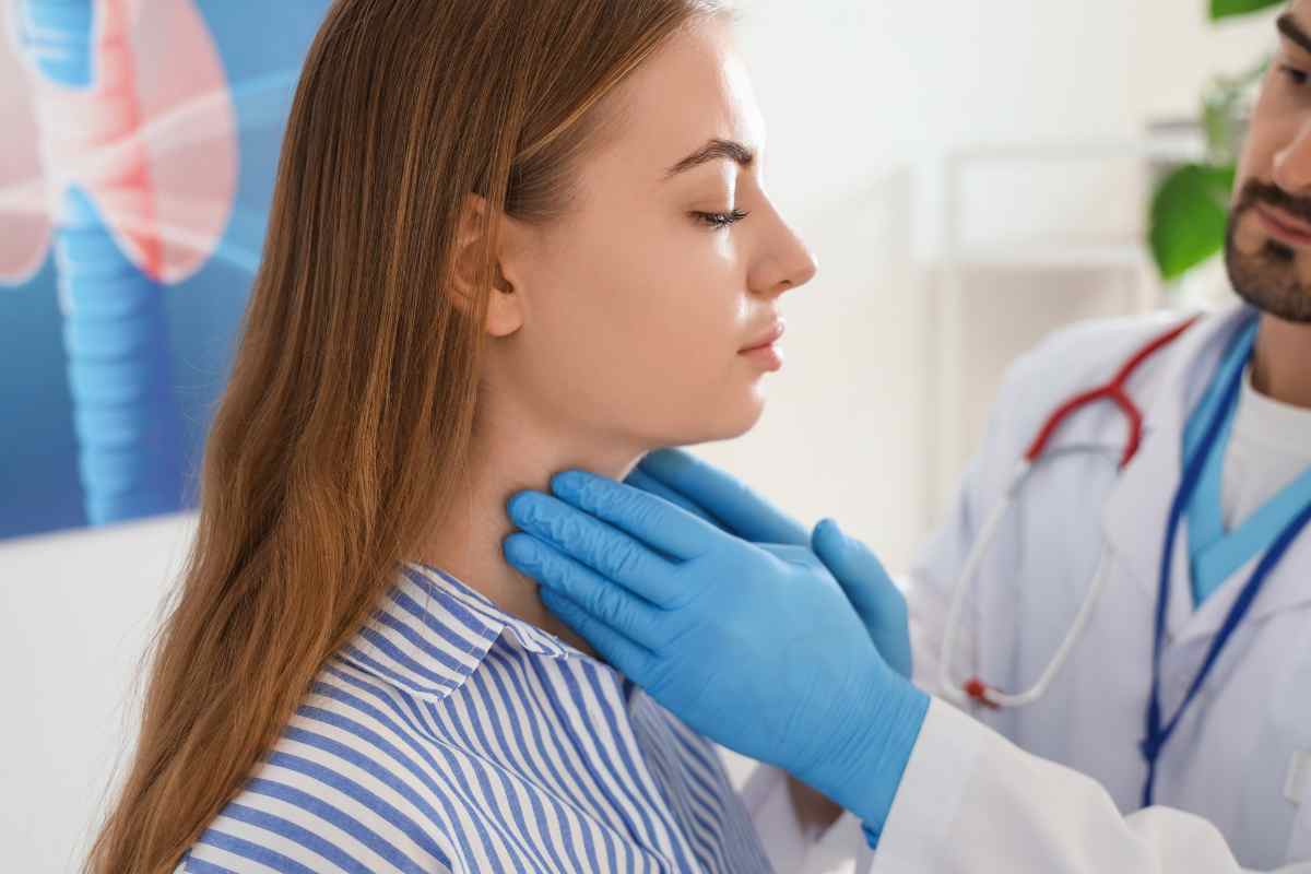un medico procede alla palpazione della tiroide a una paziente