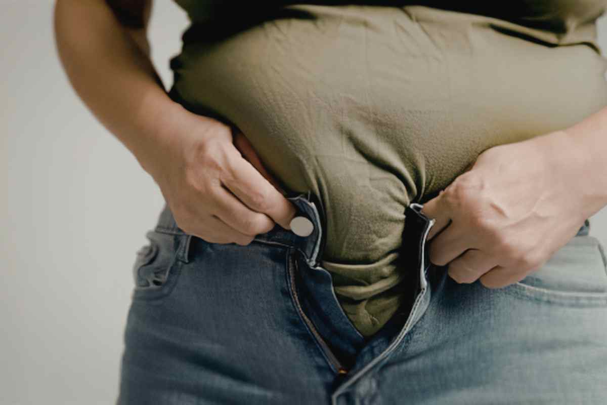 una ragazza cerca di chiudere i bottoni dei jeans