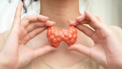 una donna mostra un plastico della tiroide