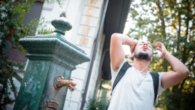 un ragazzo si bagna la testa per sopportare meglio il caldo in città