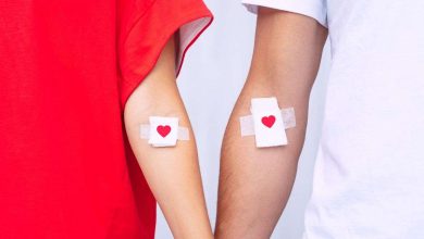 due persone si tengono la mano e fanno vedere l'interno delle braccia con cerotti in corrispondenza del punto in cui c'è stato prelievo di sangue