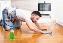 un uomo pulisce carponi il pavimento di casa