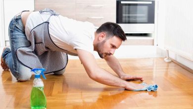 un uomo pulisce carponi il pavimento di casa