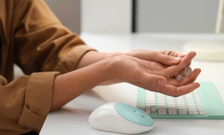 donna che si massaggia un dito perché ha il formicolio alle mani mentre lavora al computer