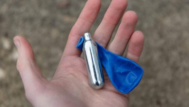 un adolescente ha in mano una confezione di gas esilarante e un palloncino