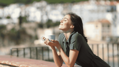 donna che beve un caffè in tazza grande su una terrazza mentre prende il sole