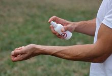 un uomo spruzza del repellente per insetti sul polso
