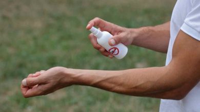 un uomo spruzza del repellente per insetti sul polso