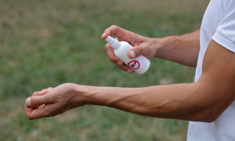un uomo spruzza del repellente per insetti sul polso