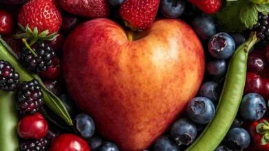 immagine con una mela a forma di cuore circondata da frutti rossi e fave fresche