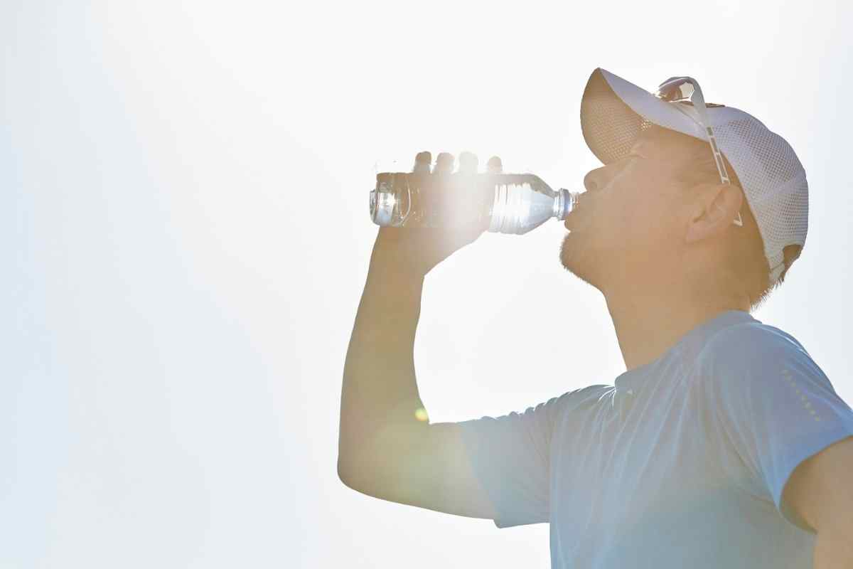 un ragazzo beve dell'acqua mentre si allena sotto il sole