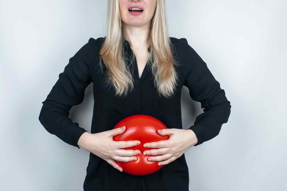 una donna che tiene davanti all'addome un palloncino rosso
