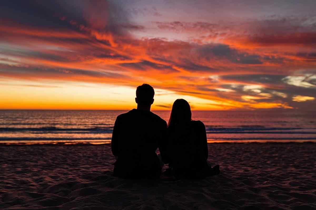 una coppia guarda abbracciata il tramonto 