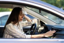 donna in macchina che ha caldo e accende l'aria condizionata mentre si asciuga il sudore dalla fronte