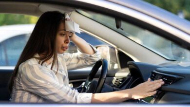 donna in macchina che ha caldo e accende l'aria condizionata mentre si asciuga il sudore dalla fronte