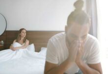 coppia a letto: la donna guarda fuori dalla finestra, mentre l'uomo si mette le mani sulla faccia preoccupato per il calo del desiderio sessuale femminile