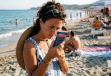 donna in spiaggia intenta a leggere l'etichetta della crema solare
