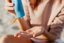 donna in spiaggia che applica la crema solare