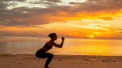 ragazza che fa gli squat sulla spiaggia, in riva al mare