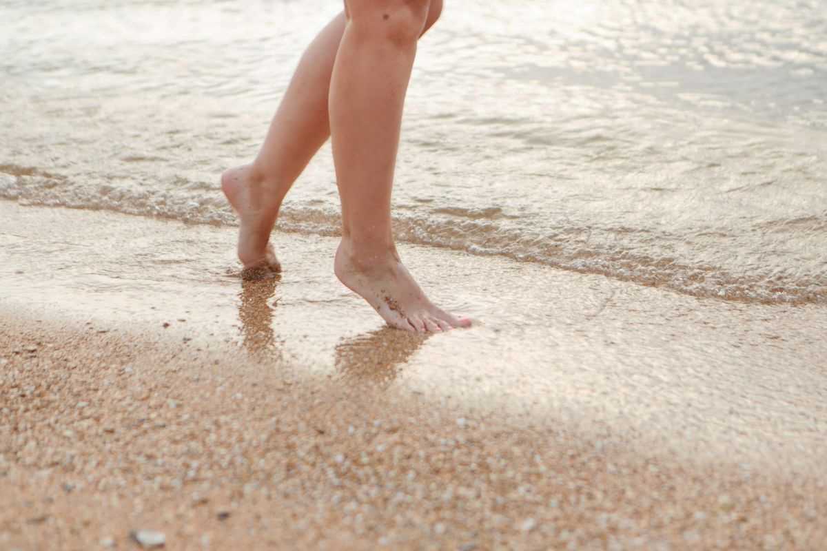 donna che fa esercizi sulla spiaggia, alternando tallone e punta