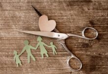 modellino in carta di famiglia con forbice che taglia il cuore per concetto di famiglia ricostruita dopo separazione