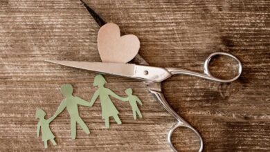 modellino in carta di famiglia con forbice che taglia il cuore per concetto di famiglia ricostruita dopo separazione