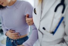 ragazza che ha mal di pancia con dottoressa che la sorregge
