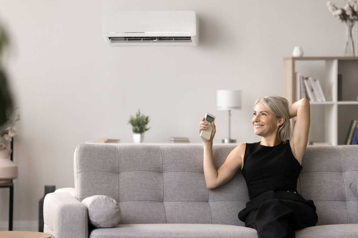 donna in menopausa che a causa del caldo accende il condizionatore di casa