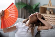 donna in menopausa che ha vampate di caldo e si sventola un ventaglio
