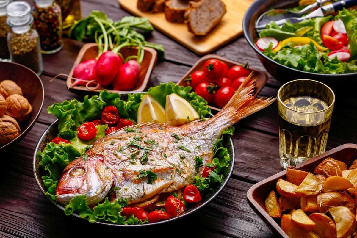 pesce cotto alla griglia appoggiato sopra a insalata e pomodorini
