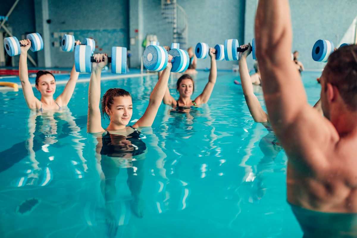 gruppo di donne che fa pilates in acqua utilizzando dei manubri per sollevamento pesi leggero