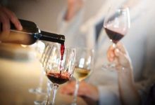 una persona versa vino in diversi bicchieri