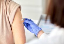 dottoressa che mette un cerotto sul braccio di una donna che si è appena sottoposta a vaccinazione in estate